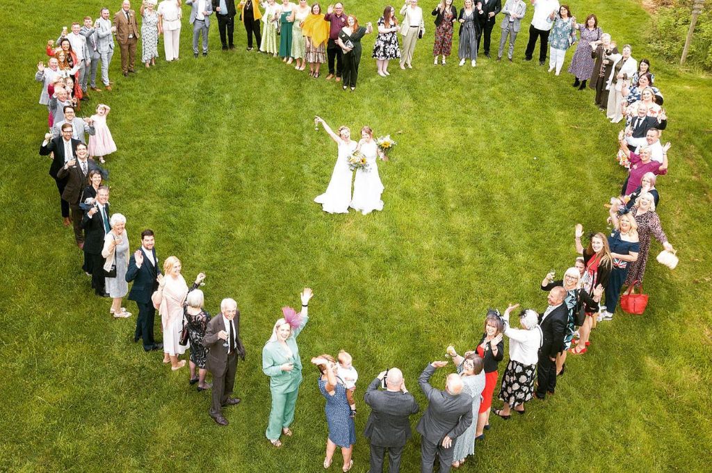 two brides stood in heart made of people